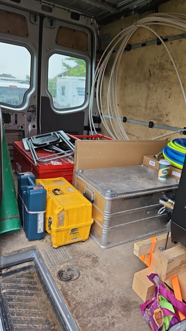Werkzeug und Materialien in einem Transporter, darunter Kisten und Leitern.